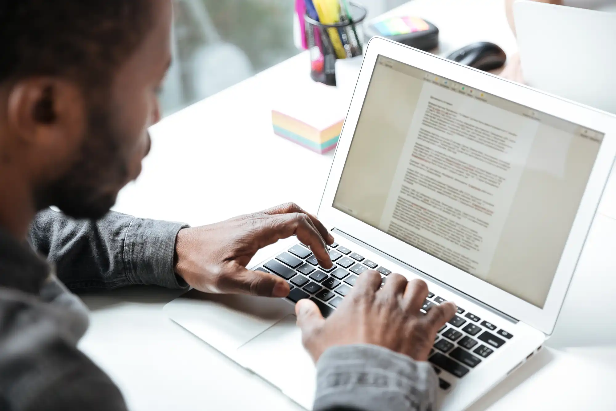 Un homme qui écrit sa lettre de motivation sur ordinateur